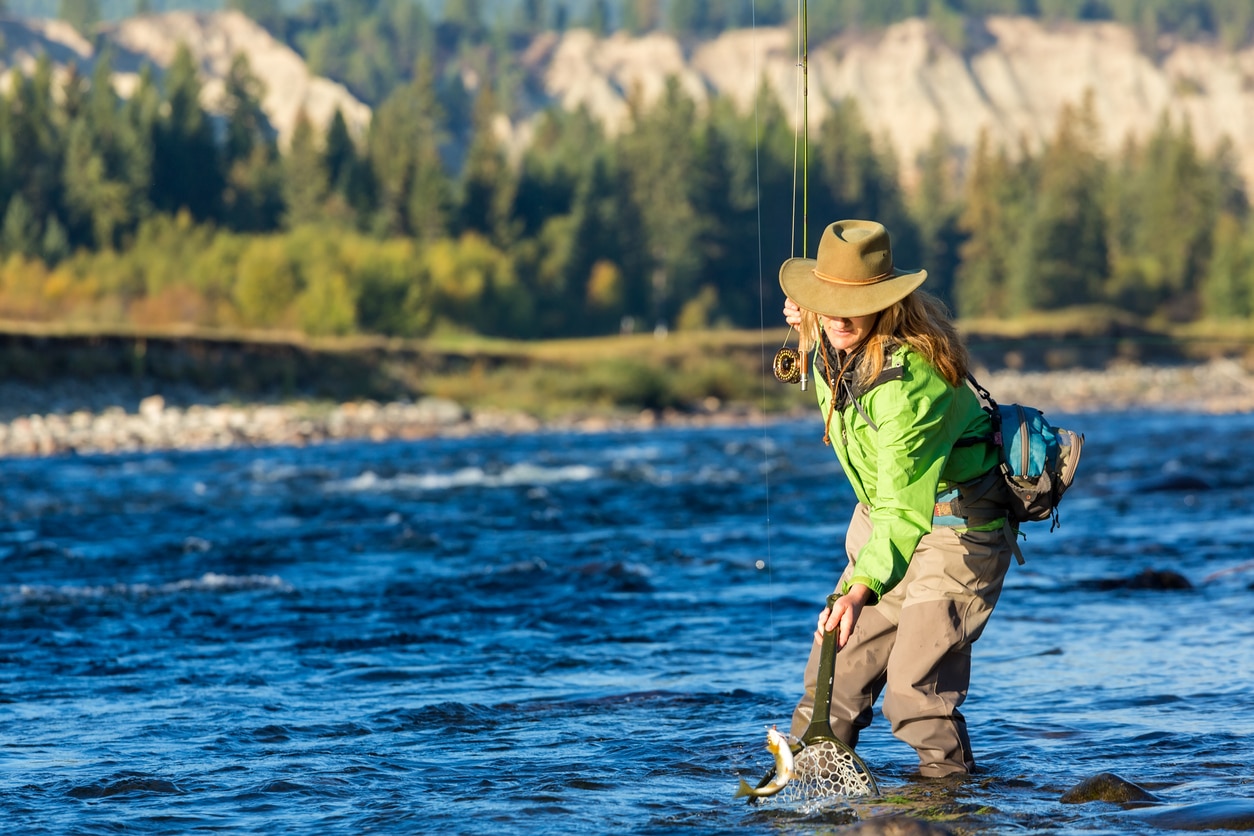 Fly fisherwoman landing trout with net British Colombia, Canada, North America